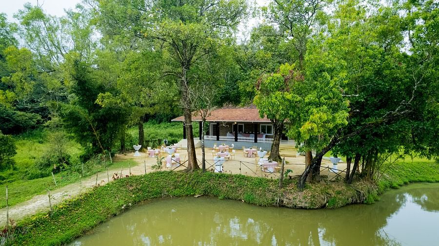 A building next to a lake with trees surrounding it at Capitol Village Resort, Madikeri
