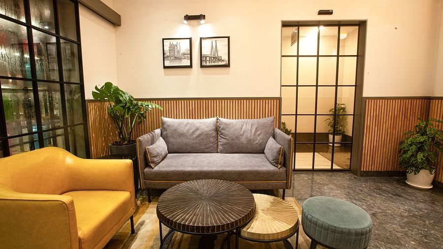 A close view of the lobby at Hotel Bawa Regency, Dadar, featuring comfy sofas, framed artwork on the wall, and indoor plants.