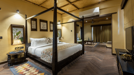 A refined bedroom at Aamaghati Wildlife Resort with a four poster bed, warm lighting, and elegant interiors offering a restful retreat.