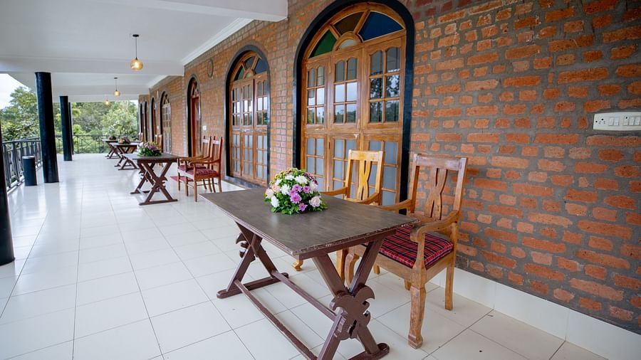Chairs & Tables in the balcony with open brick walls - Capitol Village Resort, Madikeri