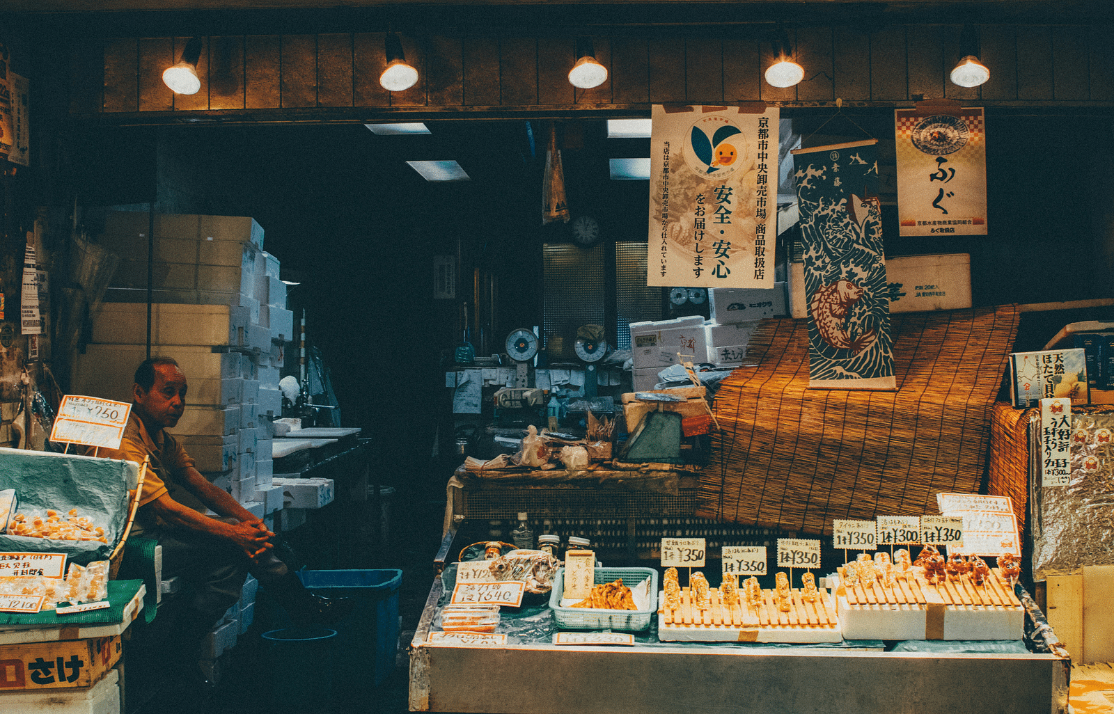 A market place with vegetable shops the vendor is also sitting 