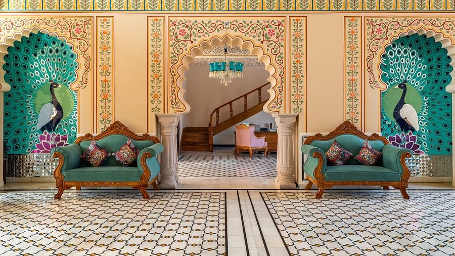 Royal seating alcove with painted arches and teal tree motifs at Kesar Bagh Palace.