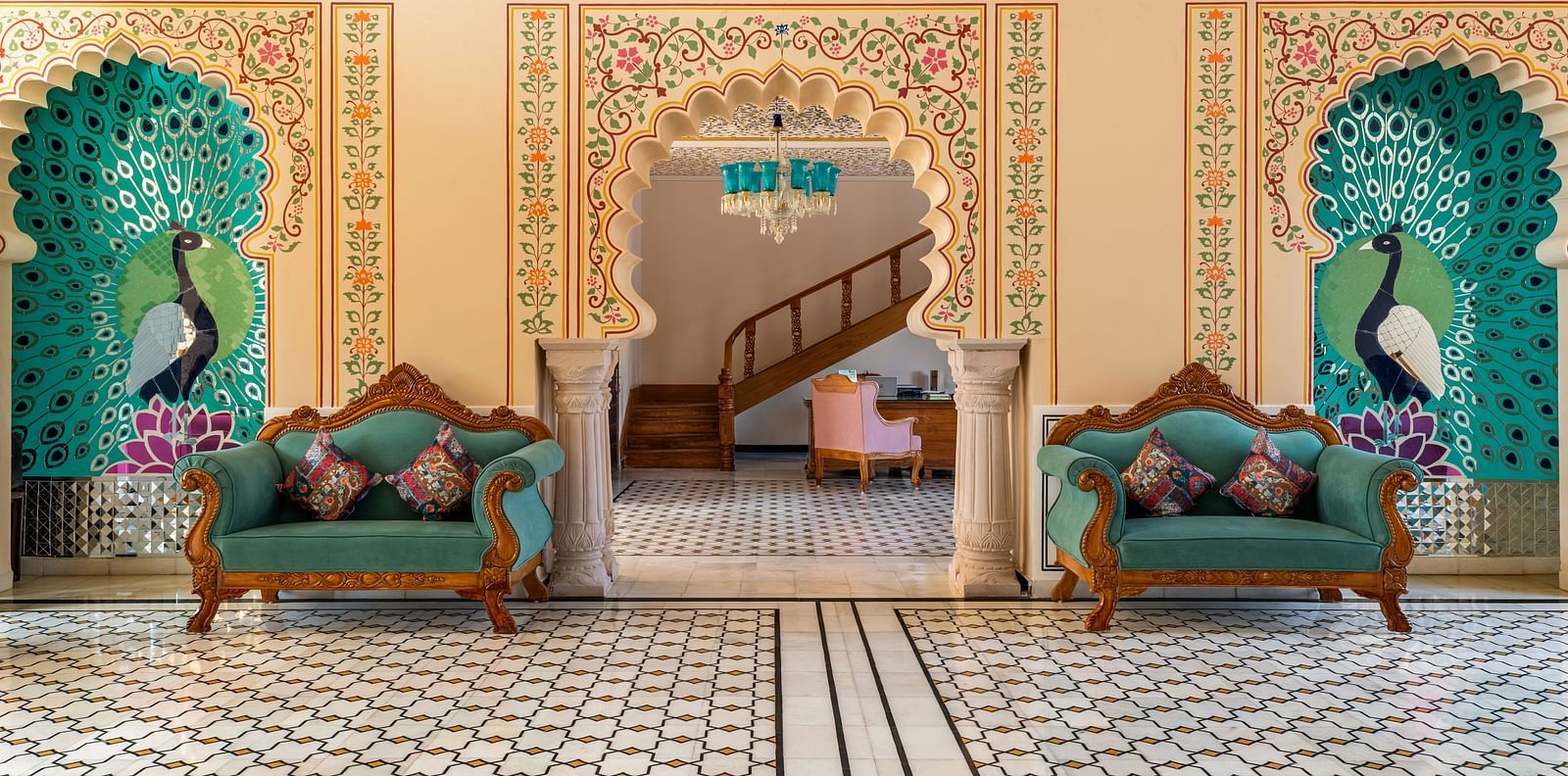 Royal seating alcove with painted arches and teal tree motifs at Kesar Bagh Palace.