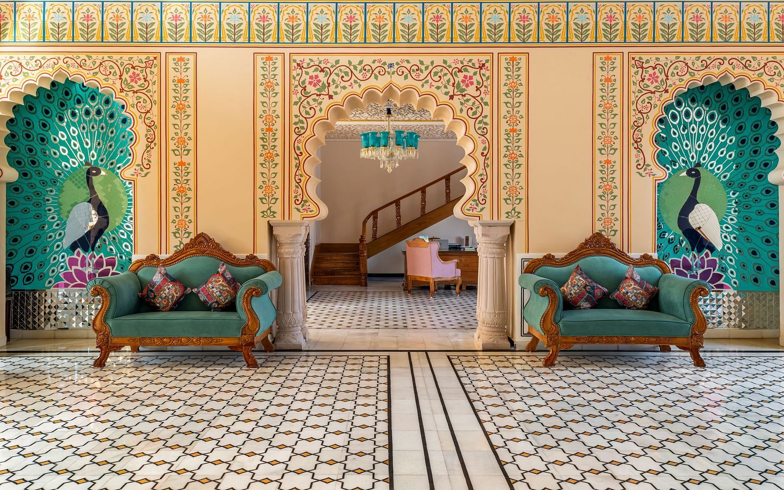 Royal seating alcove with painted arches and teal tree motifs at Kesar Bagh Palace.