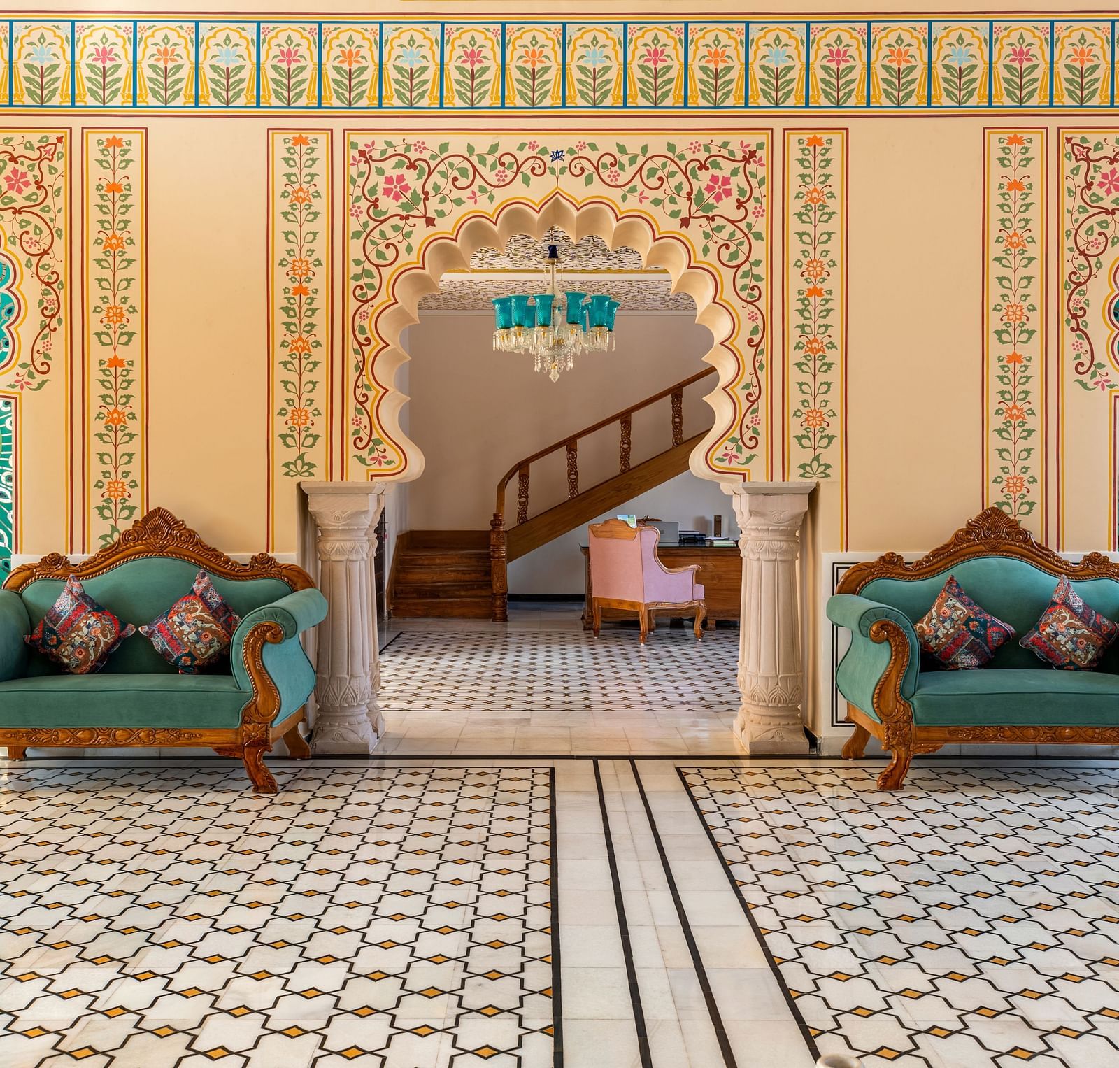 Royal seating alcove with painted arches and teal tree motifs at Kesar Bagh Palace.