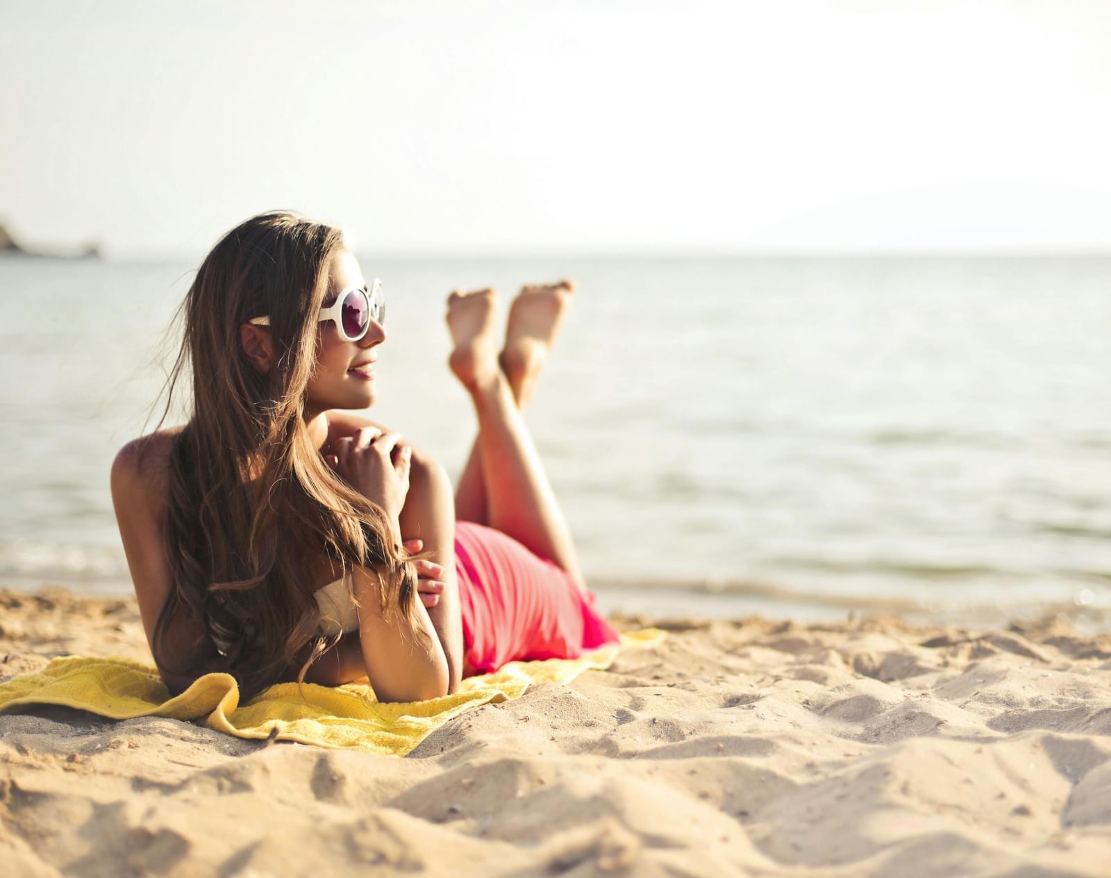 A person relaxing on a sunny beach, looking out at the sea.
