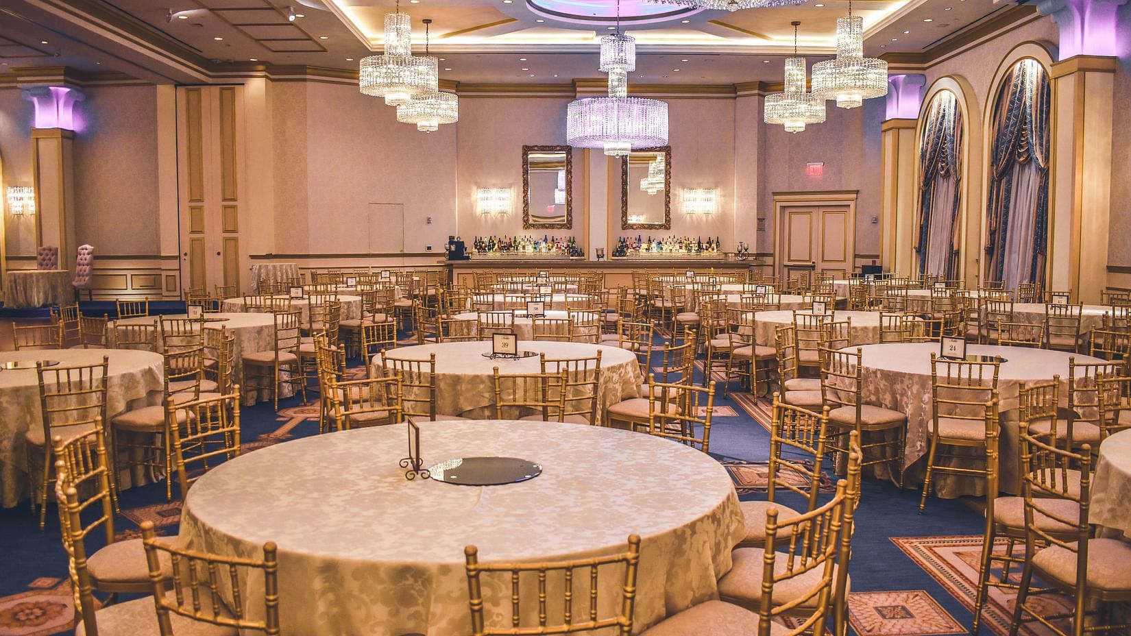 a bunch of round tables placed along with chairs in an event venue