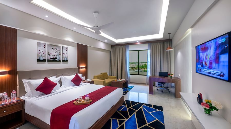Comfortable huge room with bed, artwork, and balcony access for a relaxing escape - Lords Eco Inn Shapar Rajkot