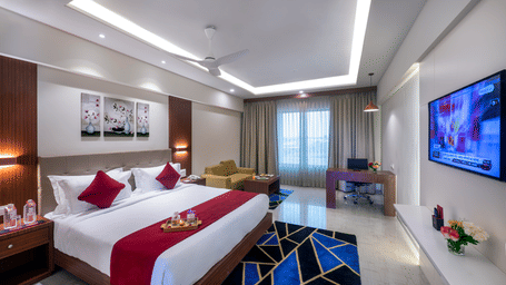 A modern hotel room in Lords Eco Inn Shapar Rajkot with a double bed, TV, and a large window offering an outdoor view