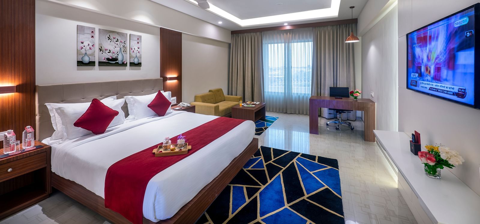 A hotel room with a bed featuring bedding, a television, and modern decor.
