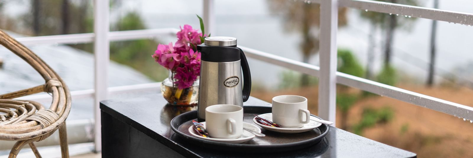 kettle and flower vase placed on a table in the balcony of Flutter Hotels & Resorts