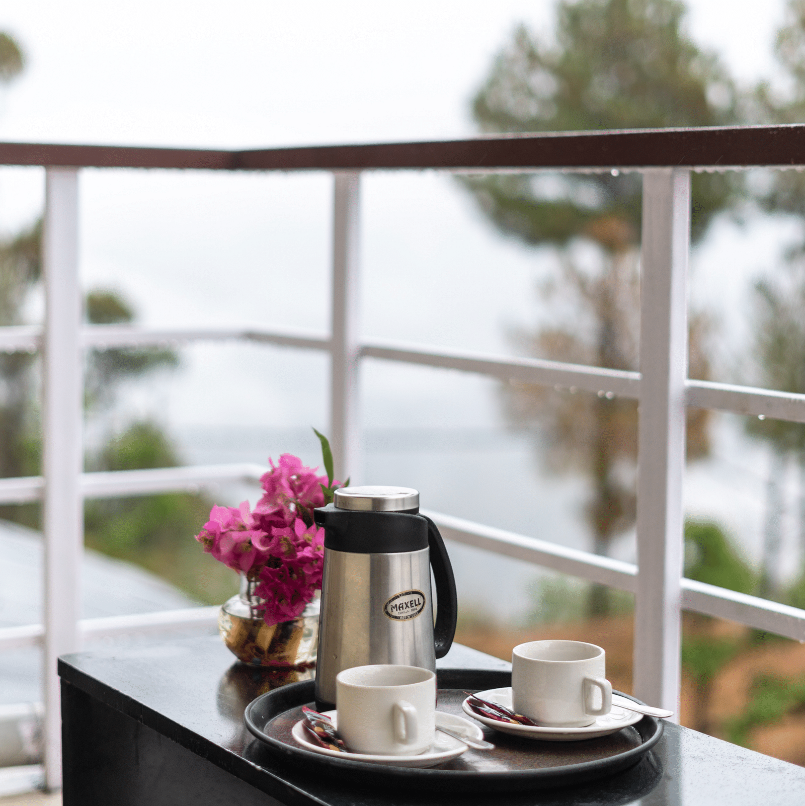 kettle and flower vase placed on a table in the balcony of Flutter Hotels & Resorts