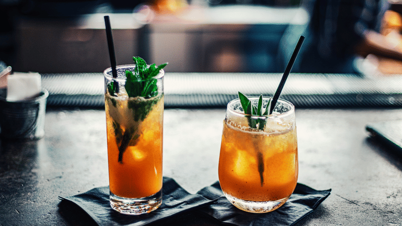 Two refreshing cocktails with mint placed on a bar counter.
