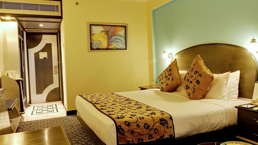 An image of a club room with double size bed with side table and lamp - The Suryaa New Delhi