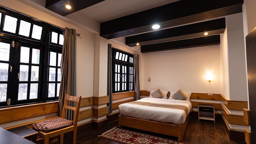 view of the deluxe room with a large bed and a chair with a window in the background at Mystique Valley Resort  