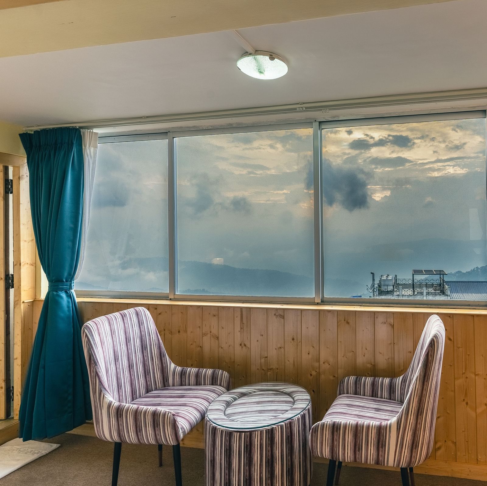 Suite with two sofa and table beside the large window at Avianna Seven Seas, Darjeeling