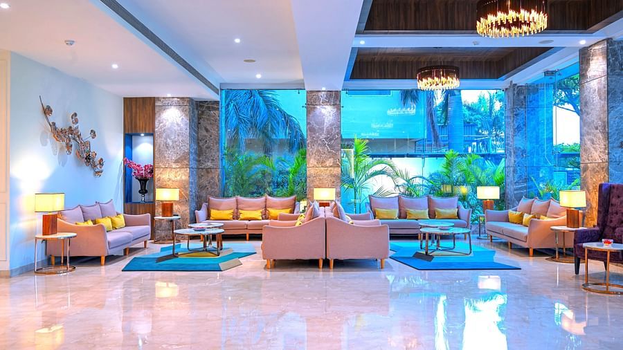 A spacious hotel lobby with comfortable couches placed around coffee tables - Golden Tulip, Agra