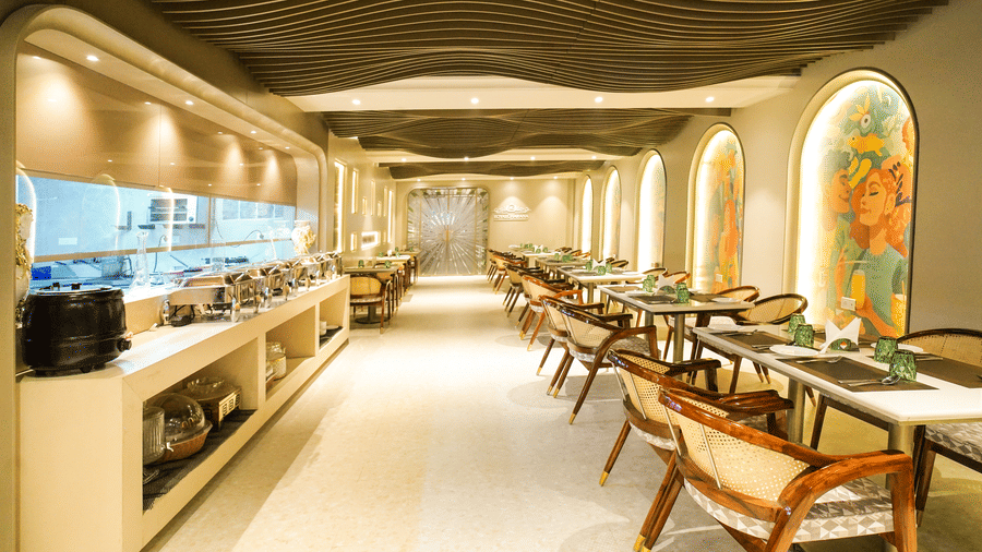 Restaurant corridor with buffet counter, dining tables, and arched wall artwork at Nirvana Gateway.