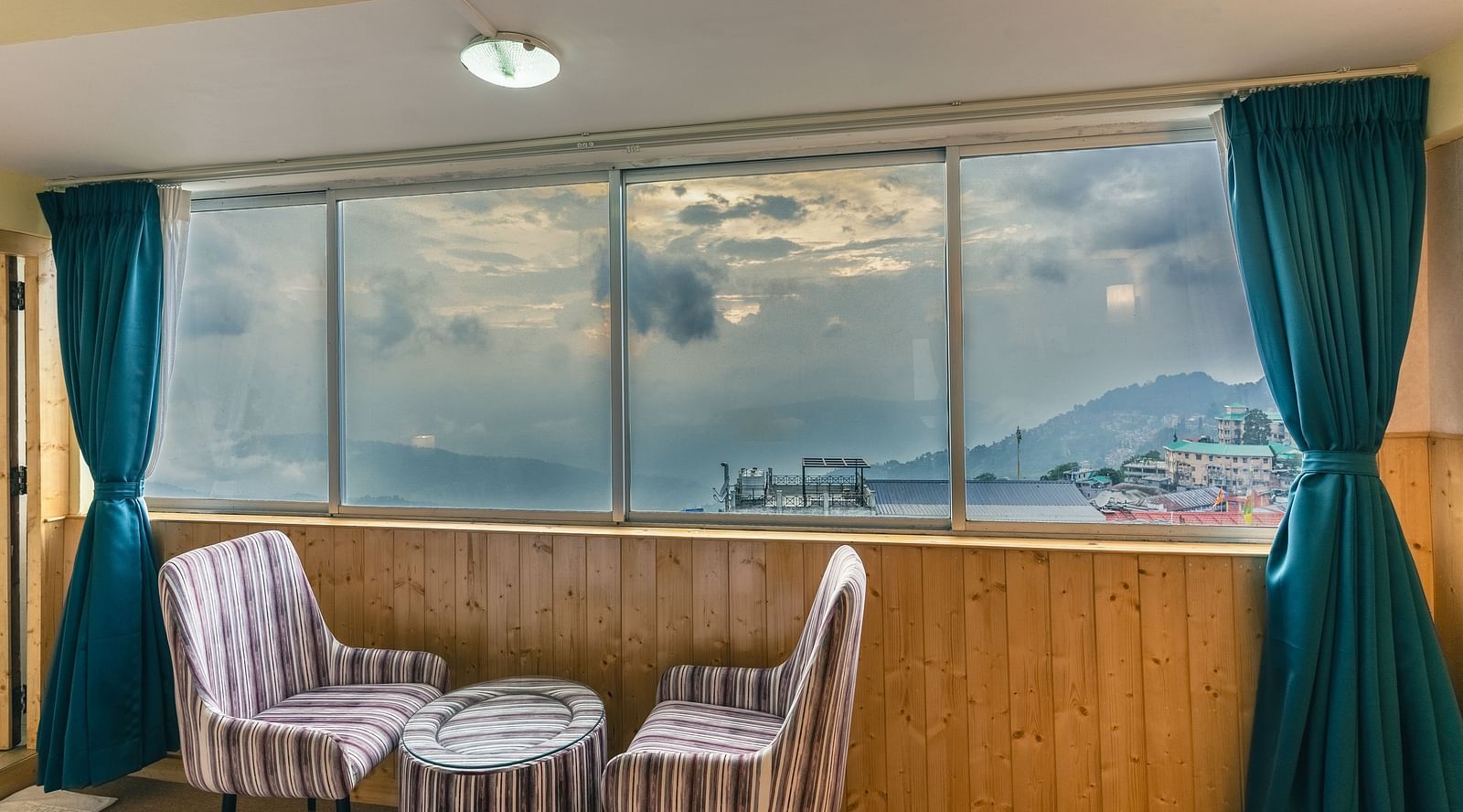 Suite with two sofa and table beside the large window at Avianna Seven Seas, Darjeeling