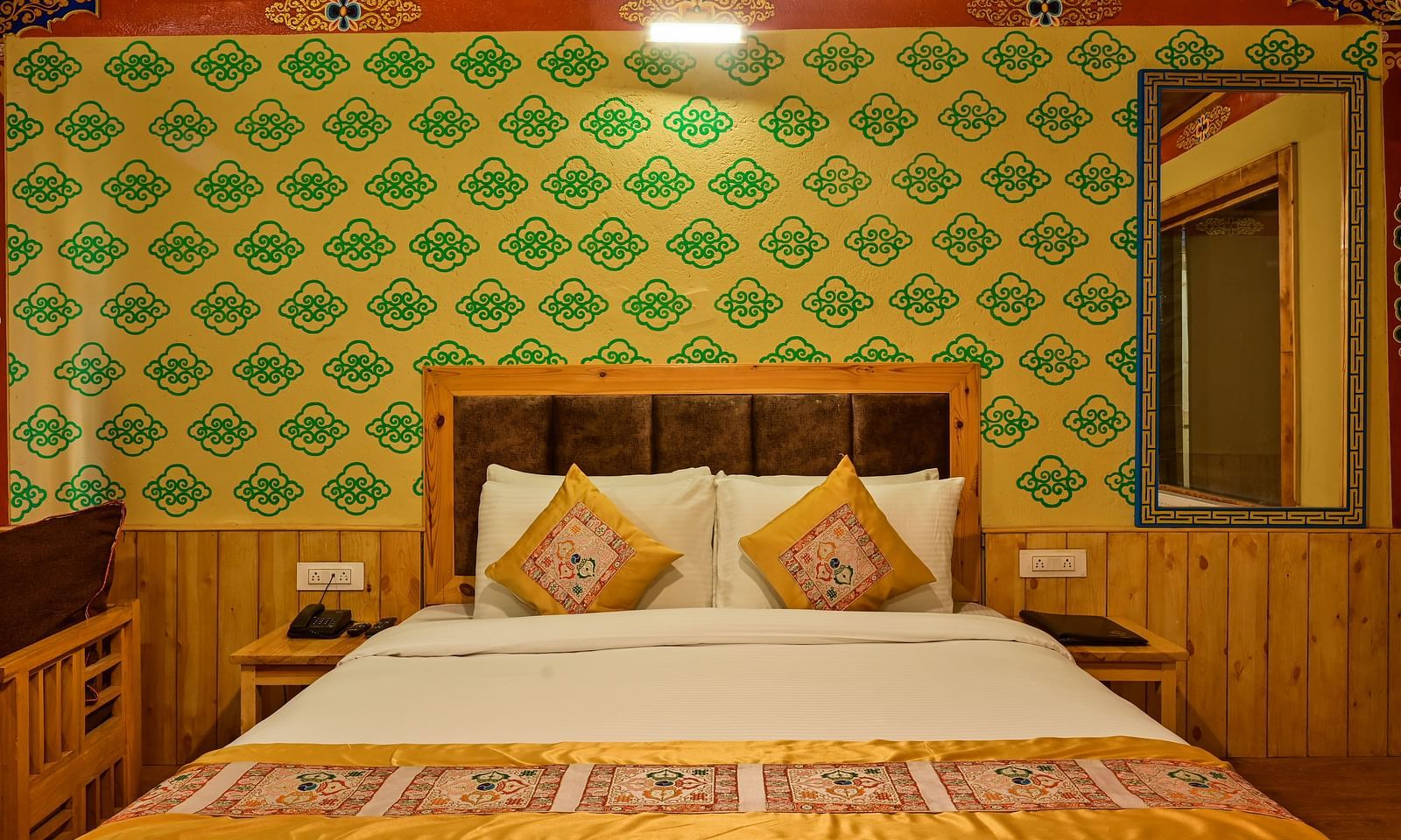 Premium Cottage in White Sands Resort, Ladakh, showcases a king size bed with patterned bedding and green patterned wallpaper.