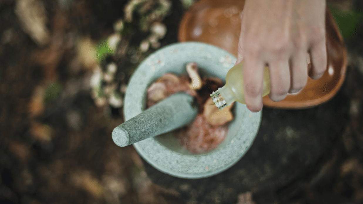 A head shot of ayurvedic herbs being crushed in a bowl