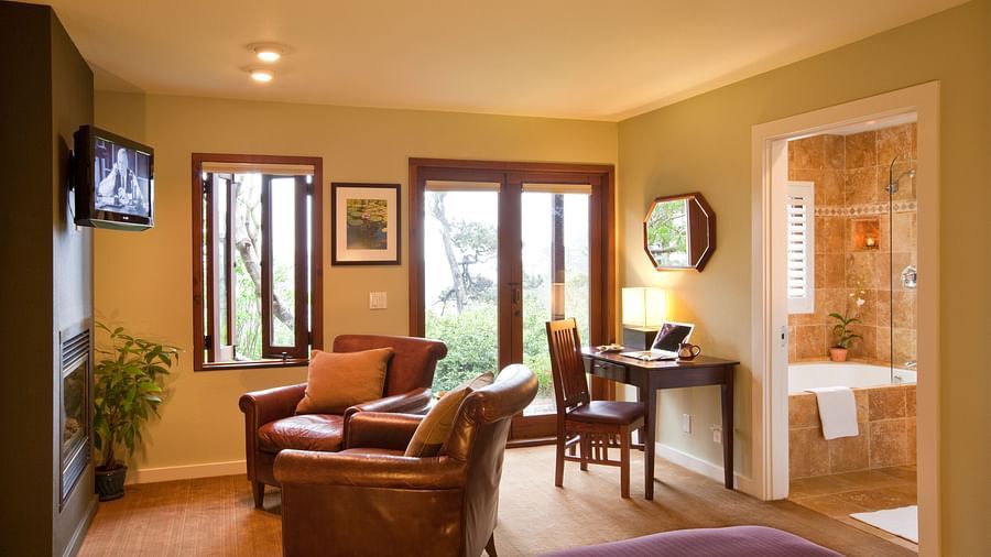 The living space in our hotel room with cozy leather chairs, a work desk and a balcony offering the views of the lush greenery surrounding our property - Brewery Gulch Inn & Spa