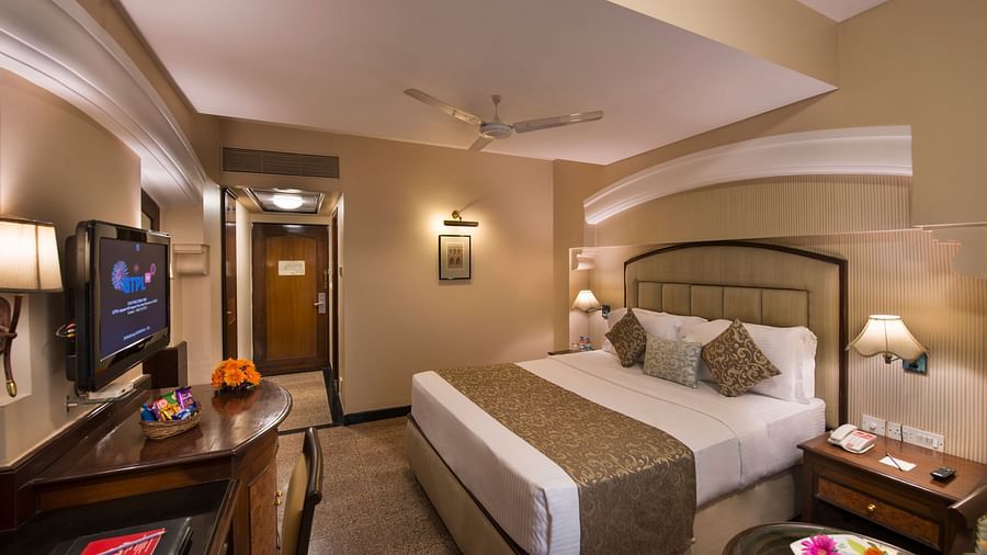 Hotel room with a bed, a nightstand, a TV, and a view into the bathroom - Lords Inn Vadodara