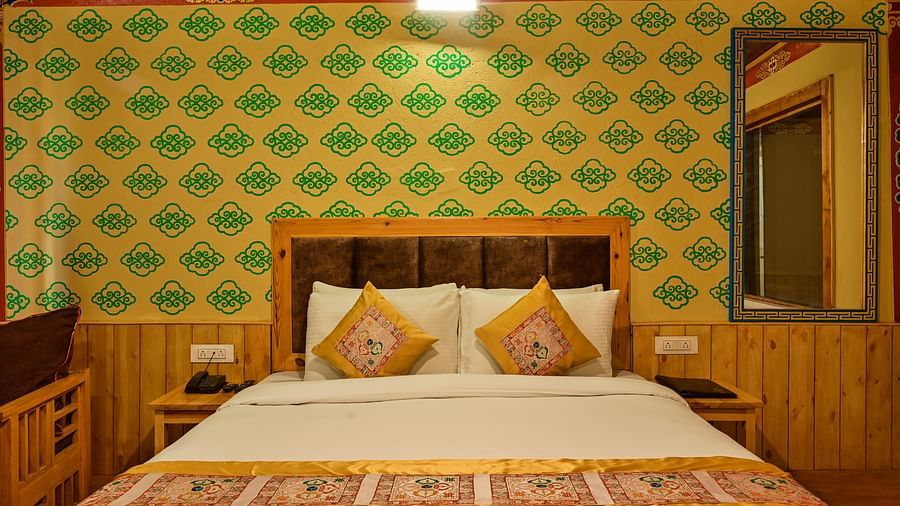 Premium Cottage in White Sands Resort, Ladakh, showcases a king size bed with patterned bedding and green patterned wallpaper.