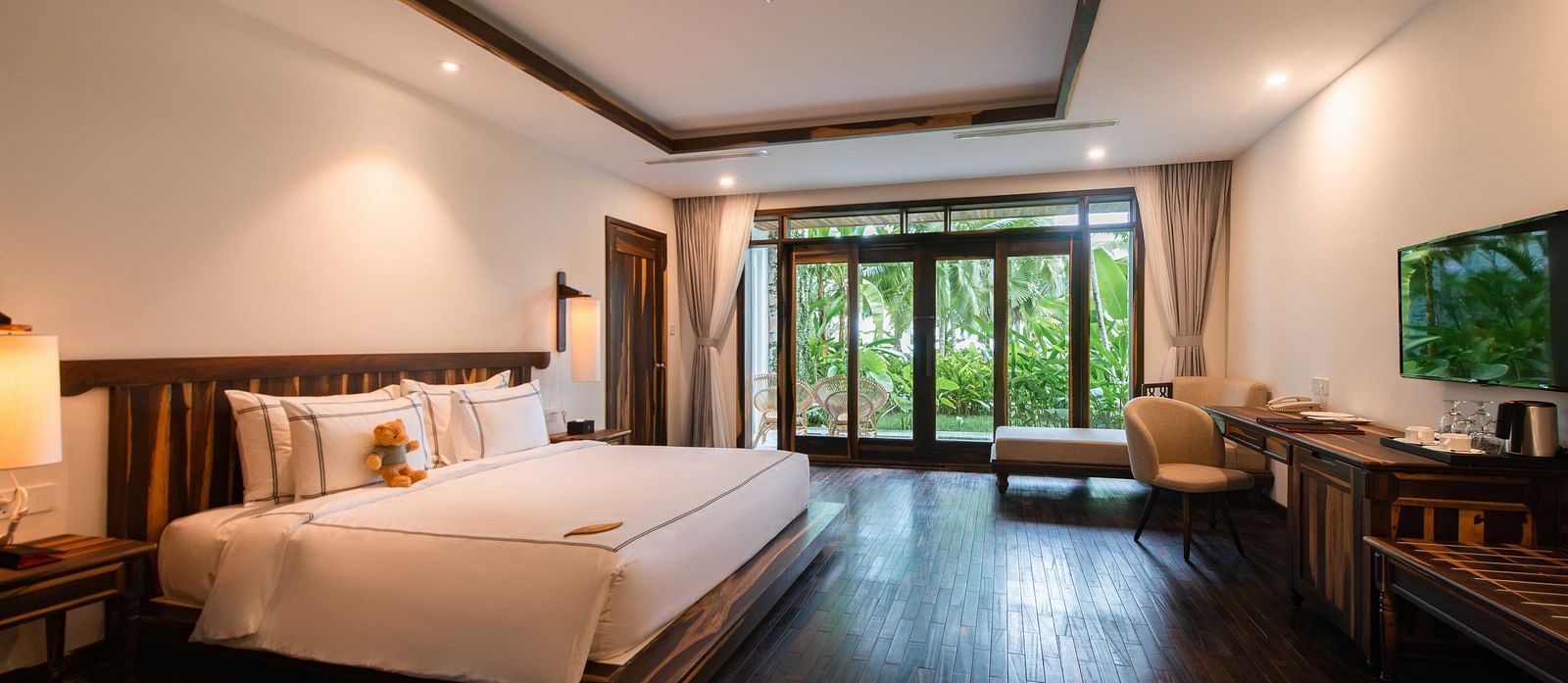 King size bed, a work desk, comfortable chair in our rooms with a garden view - Alibu Resort Nha Trang