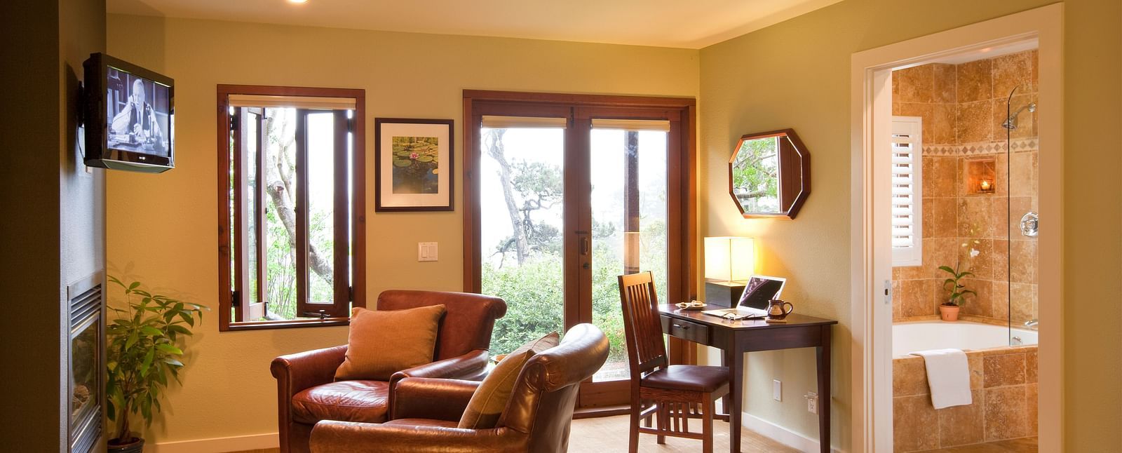 The living space in our hotel room with cozy leather chairs, a work desk and a balcony offering the views of the lush greenery surrounding our property - Brewery Gulch Inn & Spa