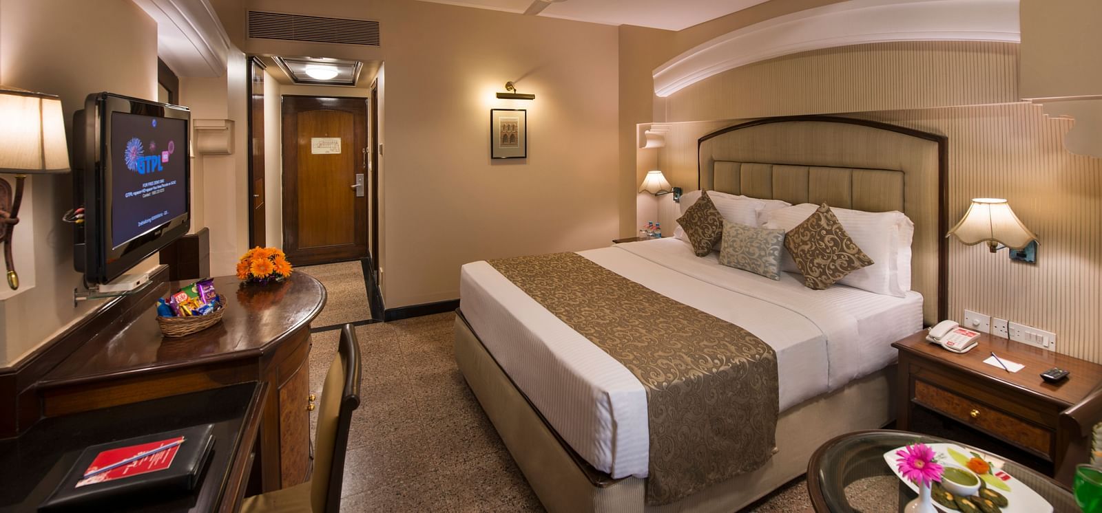 Hotel room with a bed, a nightstand, a TV, and a view into the bathroom - Lords Inn Vadodara