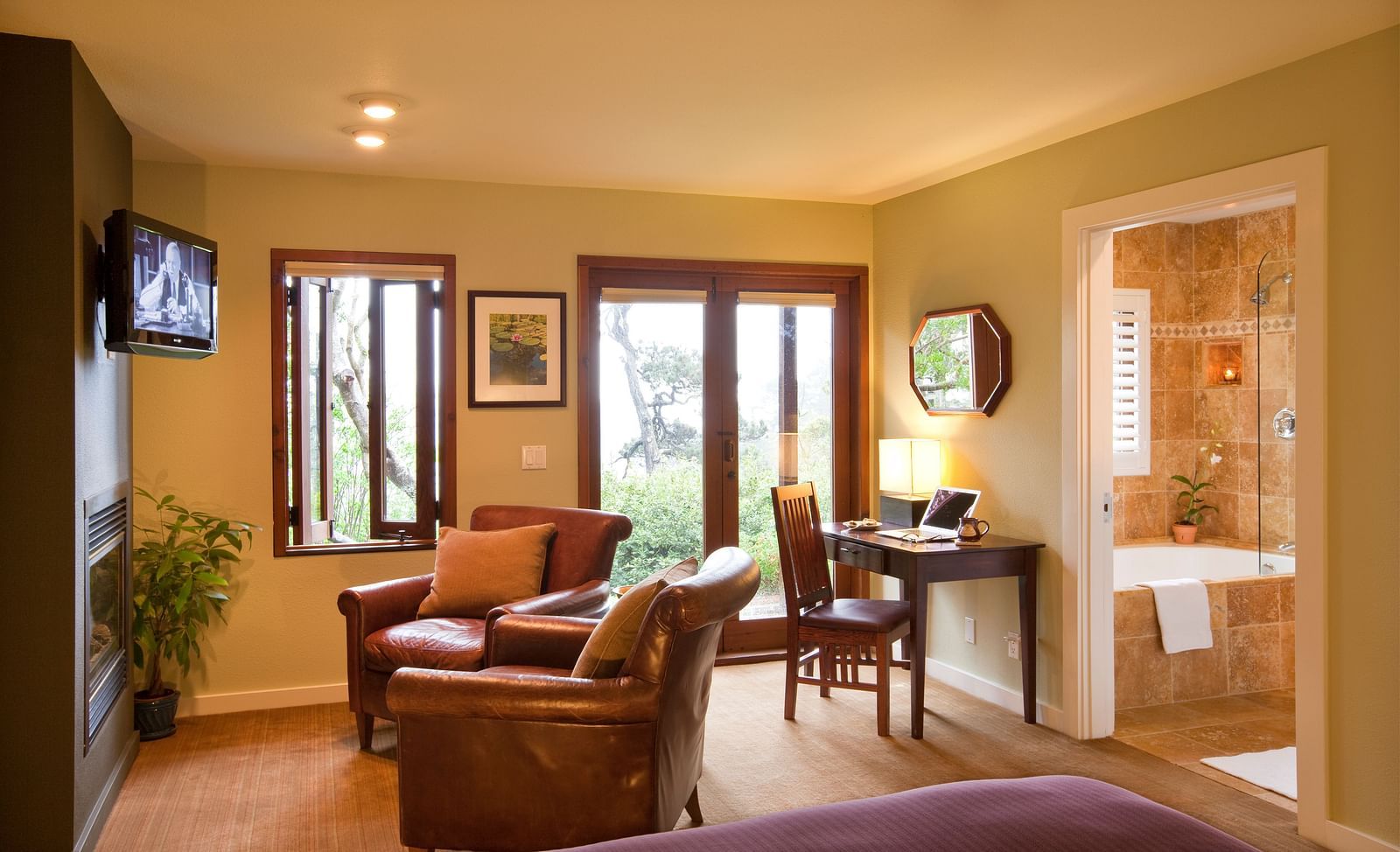 The living space in our hotel room with cozy leather chairs, a work desk and a balcony offering the views of the lush greenery surrounding our property - Brewery Gulch Inn & Spa