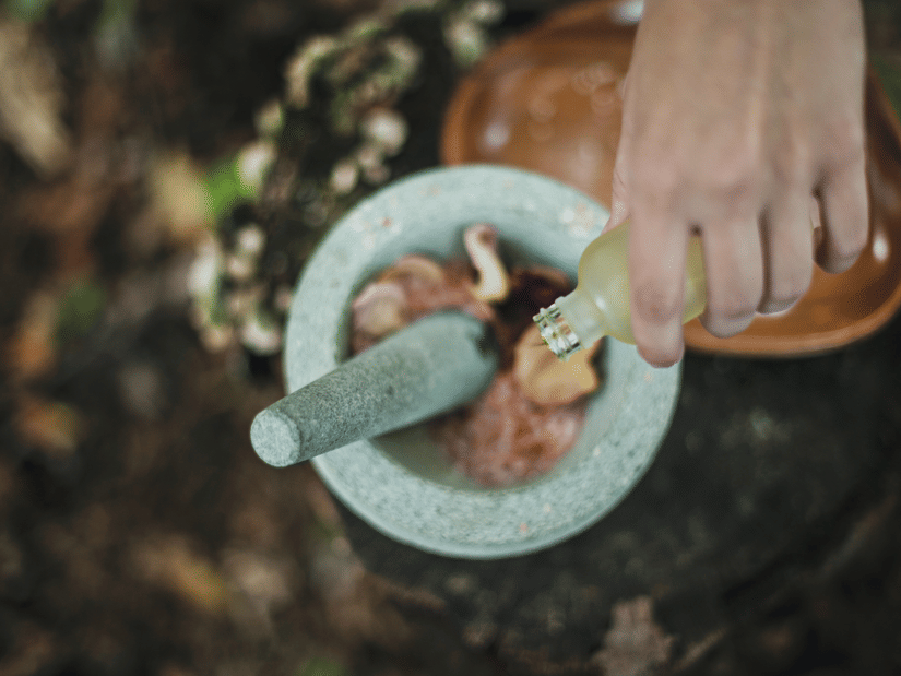 A head shot of ayurvedic herbs being crushed in a bowl