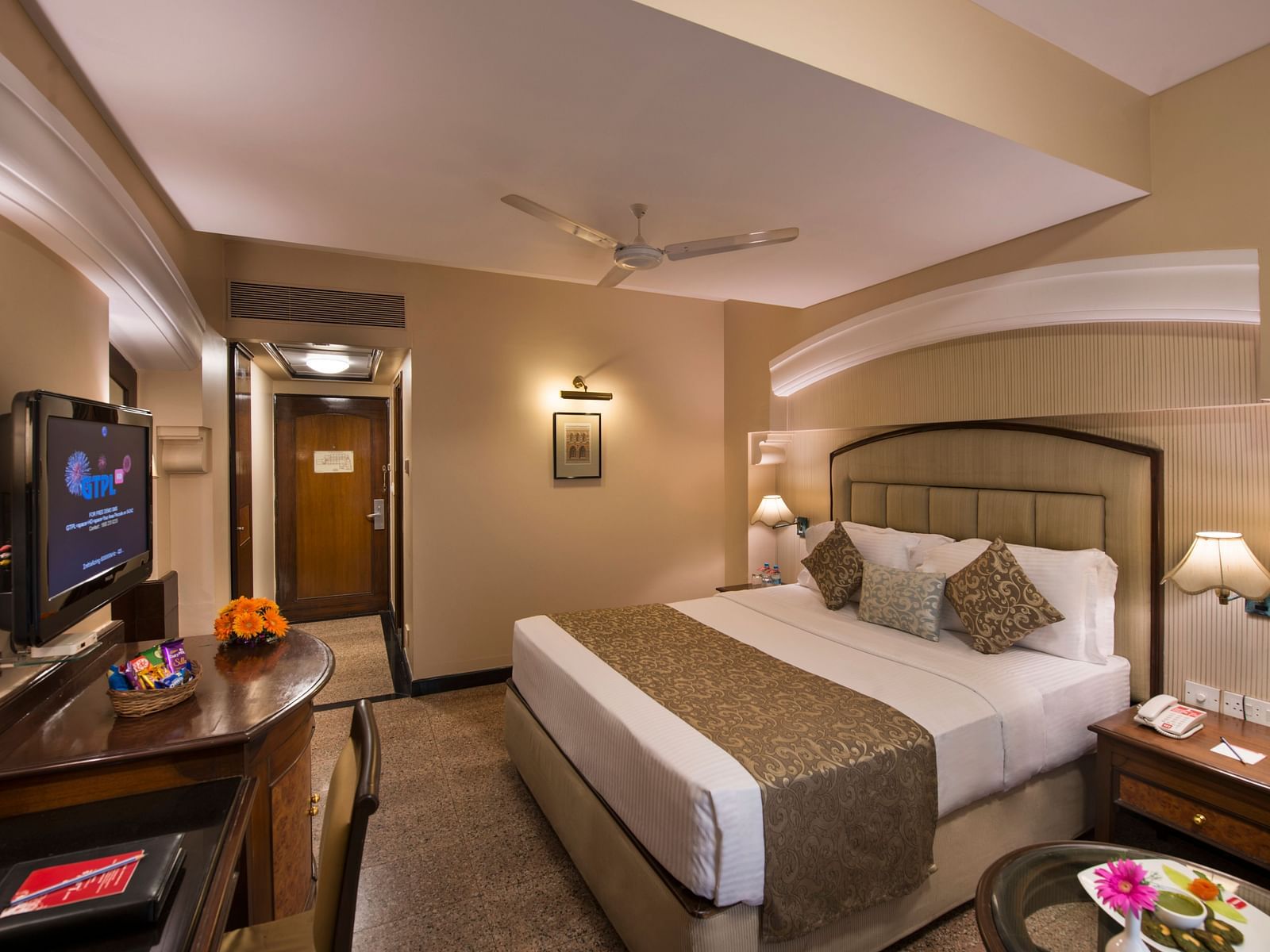 Hotel room with a bed, a nightstand, a TV, and a view into the bathroom - Lords Inn Vadodara