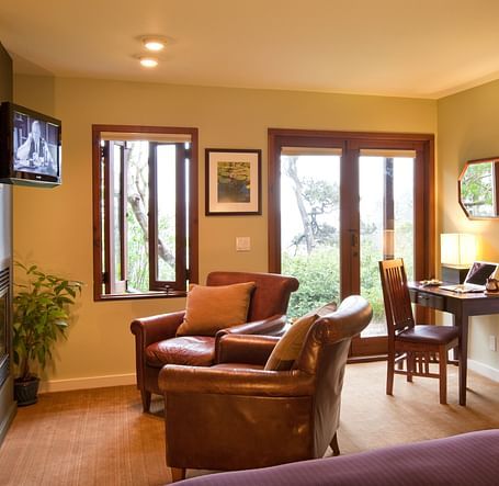 The living space in our hotel room with cozy leather chairs, a work desk and a balcony offering the views of the lush greenery surrounding our property - Brewery Gulch Inn & Spa