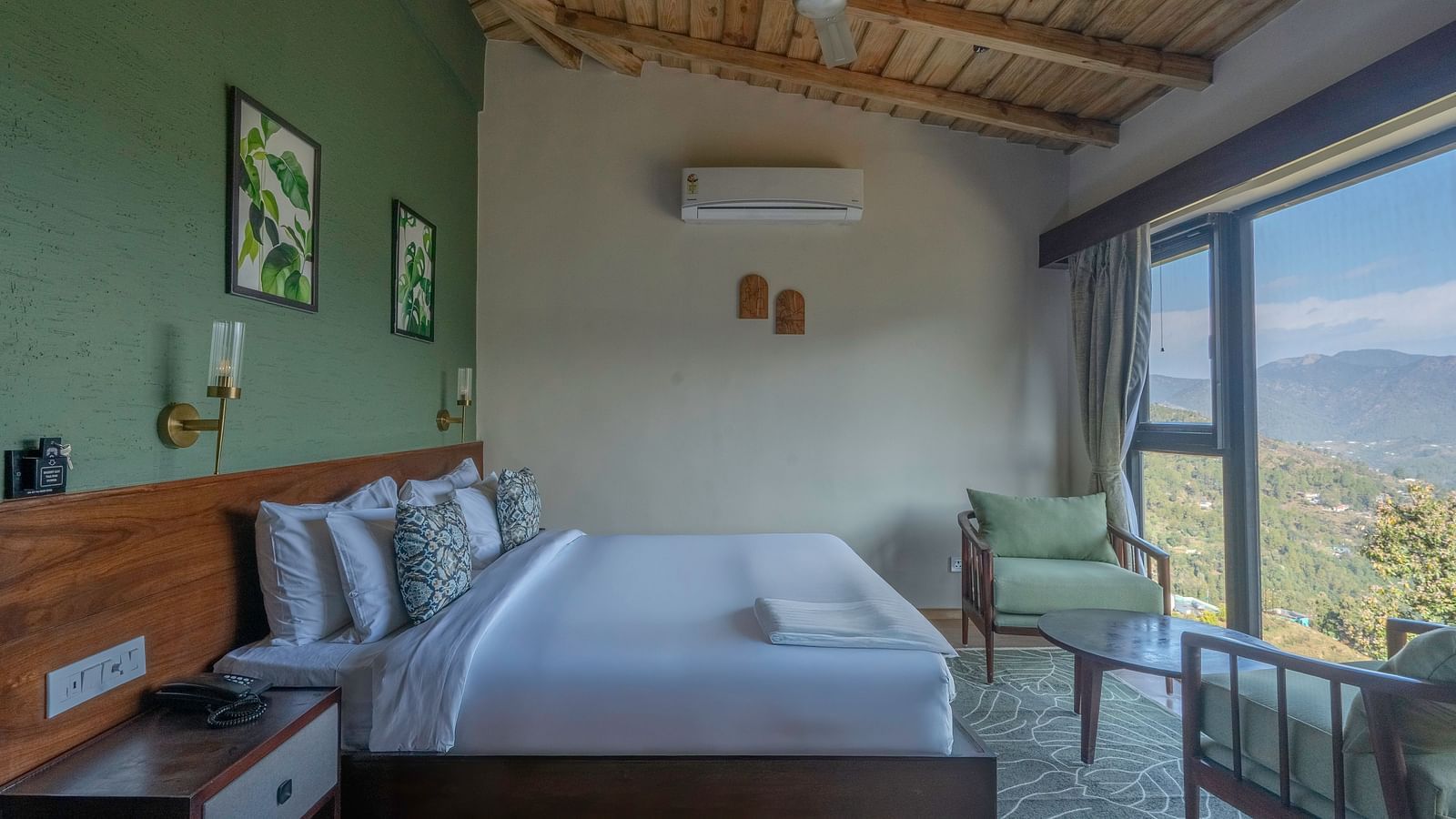 Side view of the room with a large bed and a pair of armchairs by a large window at The Chamomile Estate.