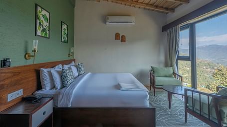 Side view of the room with a large bed and a pair of armchairs by a large window at The Chamomile Estate.