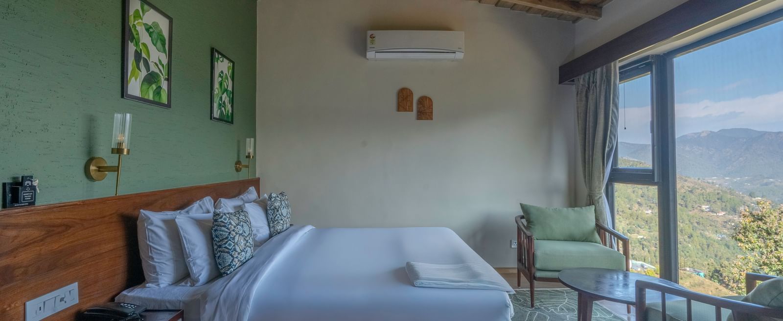 Side view of the room with a large bed and a pair of armchairs by a large window at The Chamomile Estate.