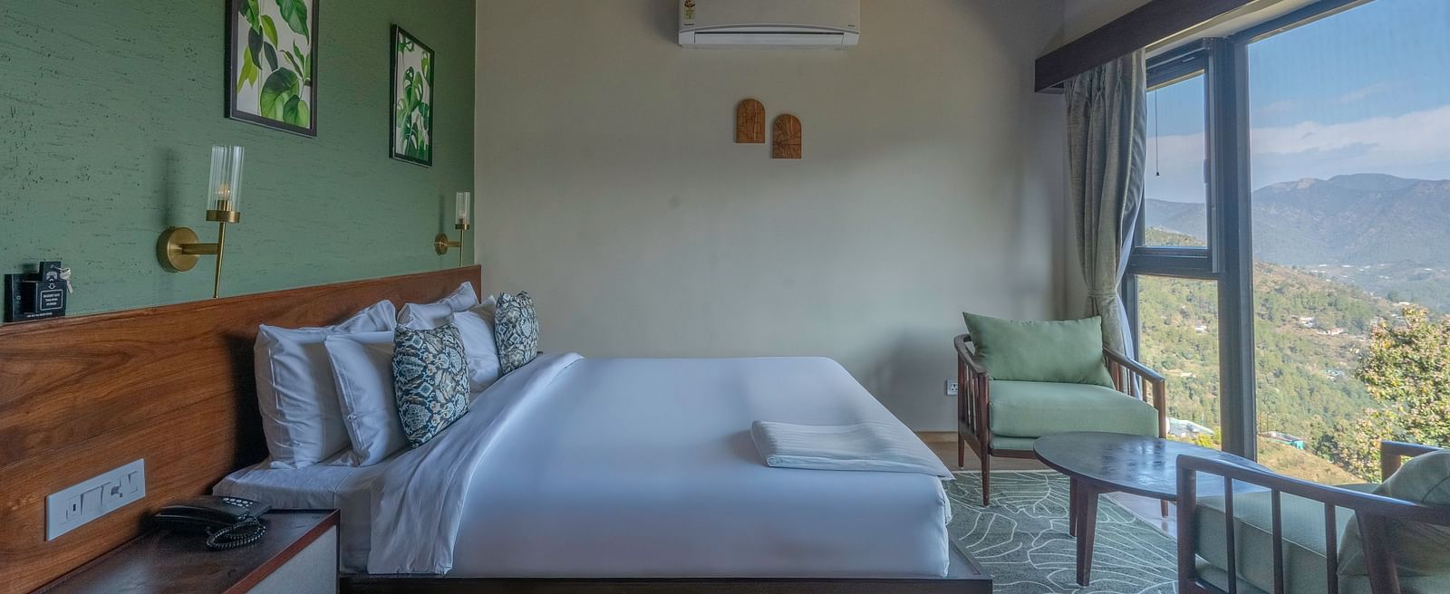 Side view of the room with a large bed and a pair of armchairs by a large window at The Chamomile Estate.