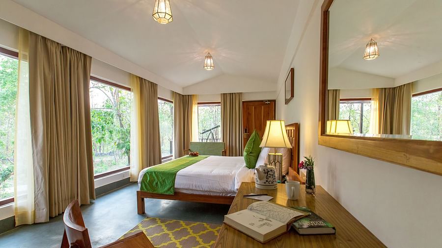 A room at Saraca Resort & Spa Corbett with a double bed overlooking the trees through large windows