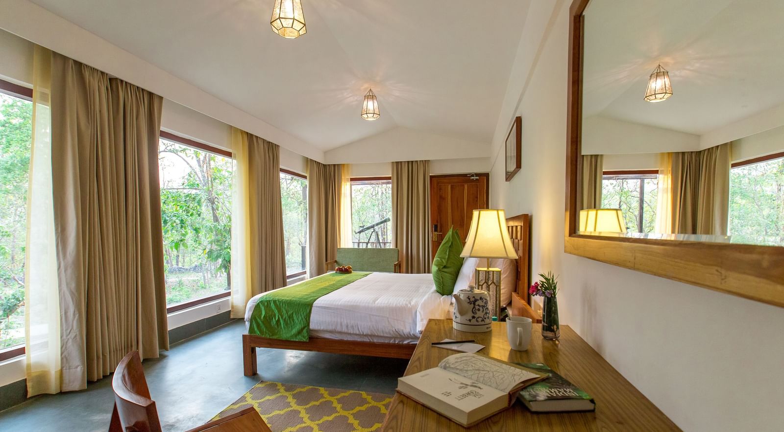 A room at Saraca Resort & Spa Corbett with a double bed overlooking the trees through large windows