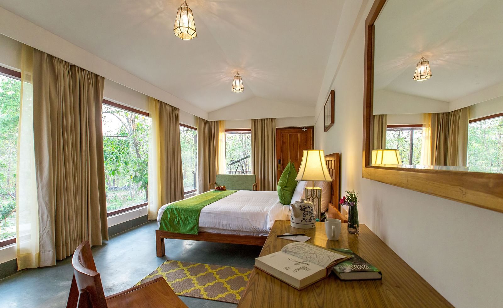 A room at Saraca Resort & Spa Corbett with a double bed overlooking the trees through large windows