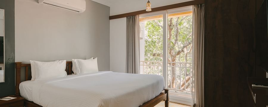 Spacious bedroom with a comfortable bed and balcony view at the Two BHK apartment in Richmonde Ananta Elite, Goa.