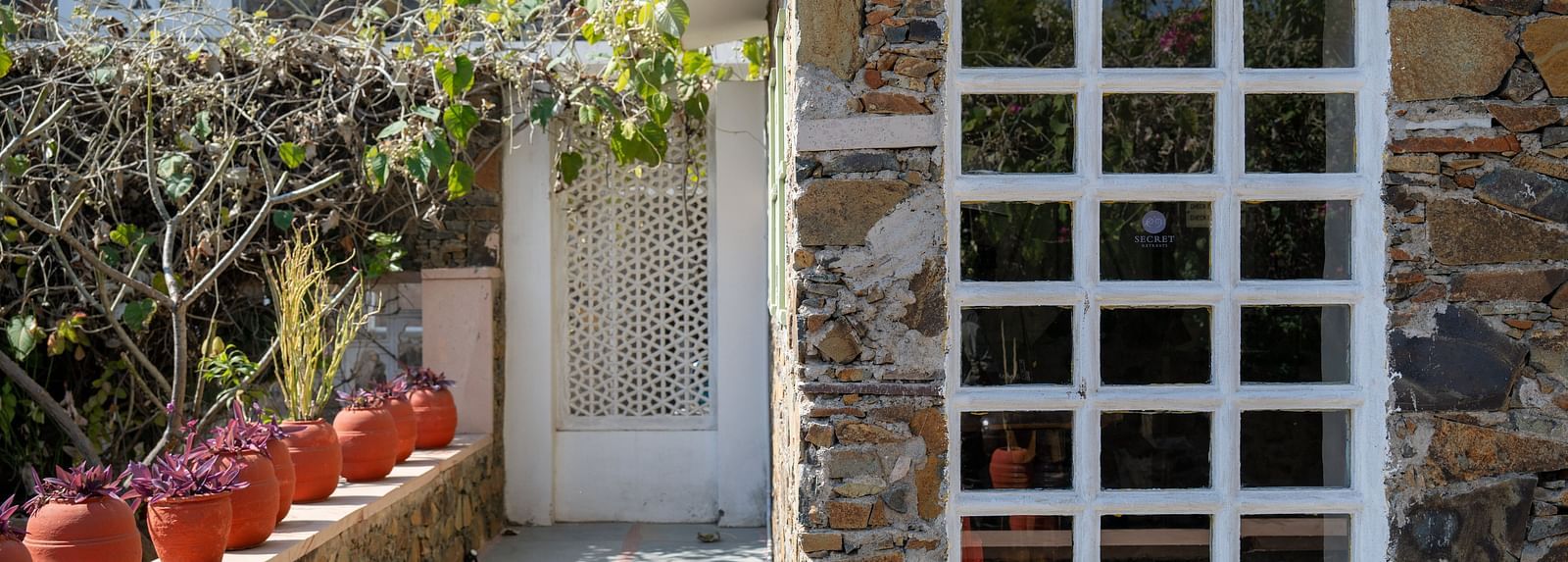 A facade image of the Utsav Camp Sariska with plants planted in tubs and are decorated in the pathway