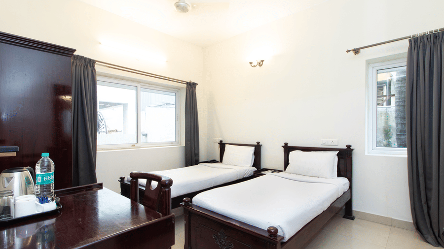 Hotel room with a double bed, a dark wooden wardrobe, and a ceiling fan at Sanctum Suites Indiranagar, Bangalore.