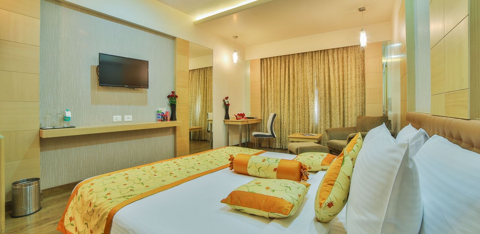 A king-sized hotel room with a contemporary design, a comfortable seating area, and a large television A grand hotel suite with an opulent red and white decor, large bed, and seating area, reflecting a traditional style at Sitara Luxury Hotel in Hyderabad 