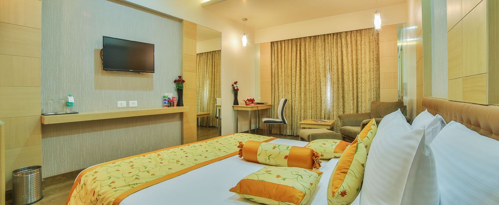 A king-sized hotel room with a contemporary design, a comfortable seating area, and a large television A grand hotel suite with an opulent red and white decor, large bed, and seating area, reflecting a traditional style at Sitara Luxury Hotel in Hyderabad 