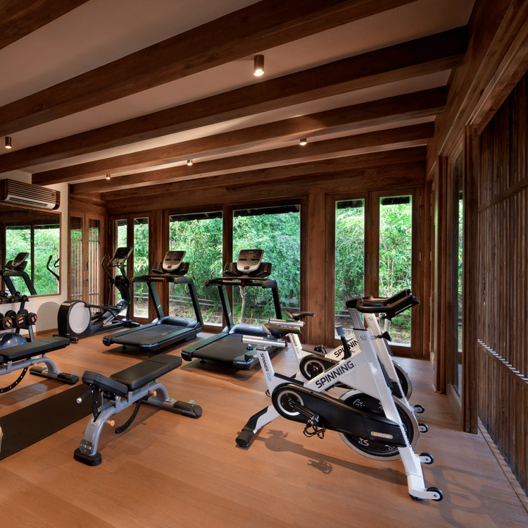 The fitness centre at Aramness features modern equipment and large windows overlooking the greenery outside.