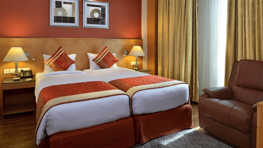 Stylish room at Savoy Suites, Manesar with warm orange accent wall, modern furnishings, and comfortable seating area