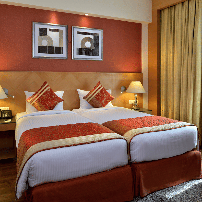 Stylish room at Savoy Suites, Manesar with warm orange accent wall, modern furnishings, and comfortable seating area
